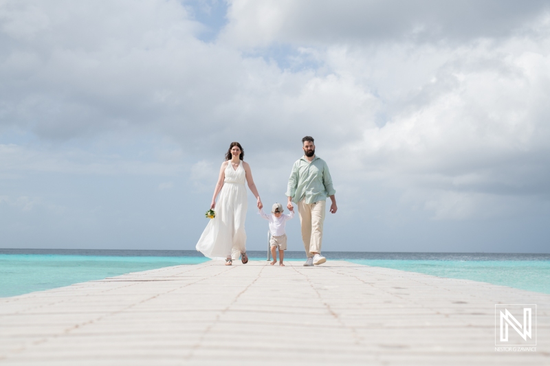 Bride and groom walking with kid at beach pier in Curacao