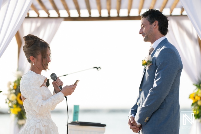 Wedding ceremony in Curacao at Sunscape Curacao Resort with couple exchanging vows by the beach under a wooden canopy