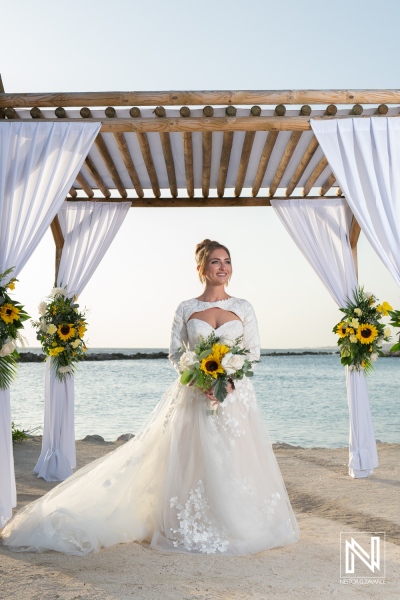 Stunning bride poses near the waterfront arch adorned with sunflowers at Sunscape Curacao Resort during a beautiful wedding ceremony