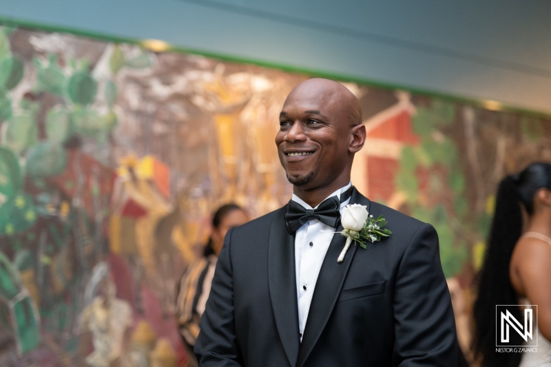 Groom at a wedding celebration in Curaçao Museum with joyful expression and stylish attire