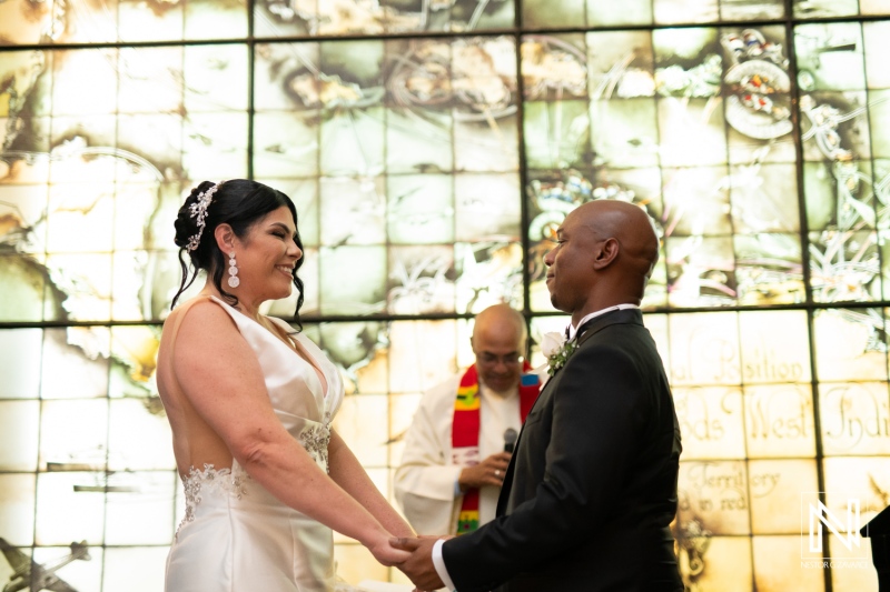 Couple exchanges vows at a beautiful wedding ceremony in Curacao at The Curacao Museum amidst vibrant stained glass backdrop