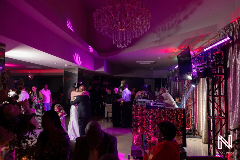 Elegant wedding celebration at the Curaçao Museum featuring guests dancing and a lively atmosphere in the evening glow