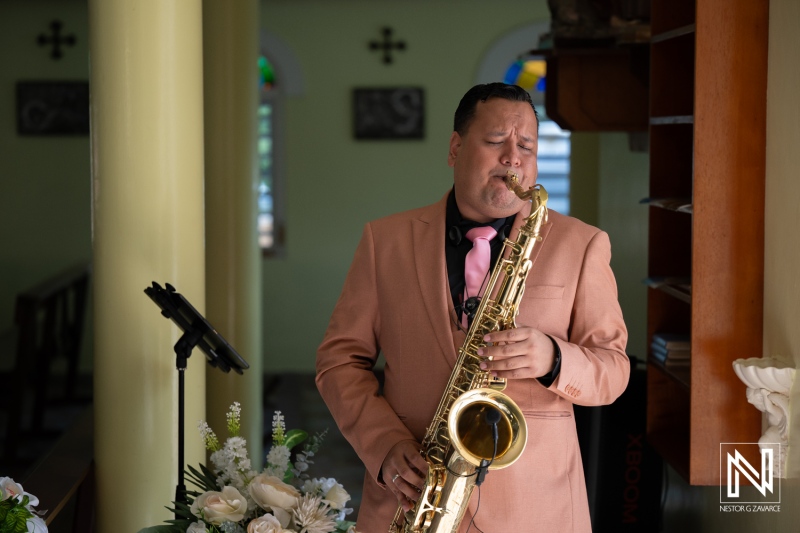 Musician plays saxophone during wedding ceremony in Curacao at a church setting in the afternoon light