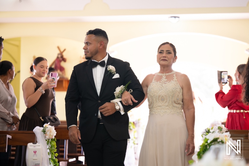 Couple walks down aisle during wedding ceremony in Curacao with family and friends present and capturing moments on their phones