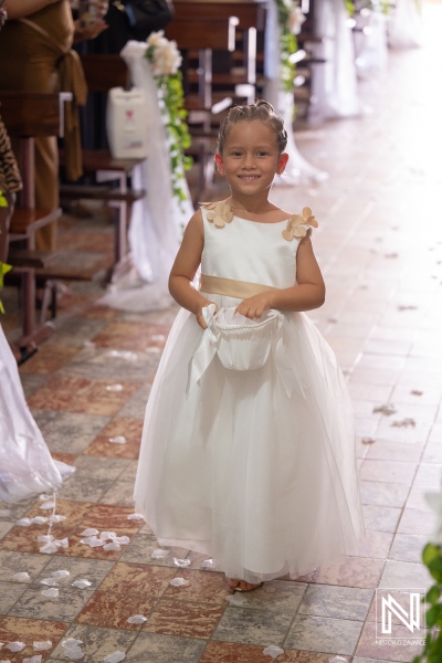 Girl walks down the aisle at a wedding in Curacao while holding a small bag
