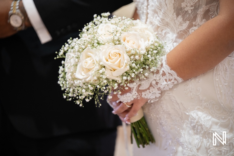 Wedding ceremony in Curacao with a bride holding a bouquet of white roses and baby’s breath flowers during the event