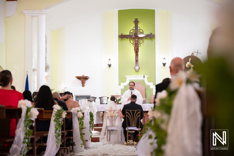 Wedding ceremony takes place inside a church in Curacao with guests seated and officiant performing the service