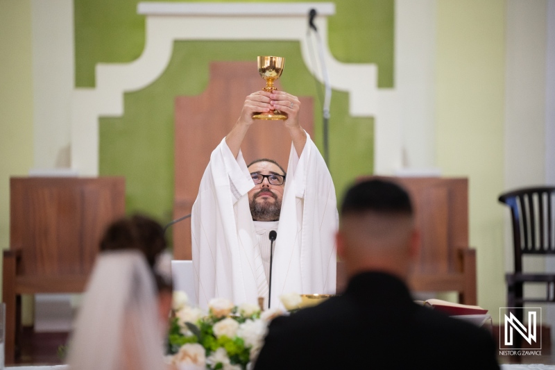 Wedding ceremony in Curacao takes place with priest holding chalice high during important moment