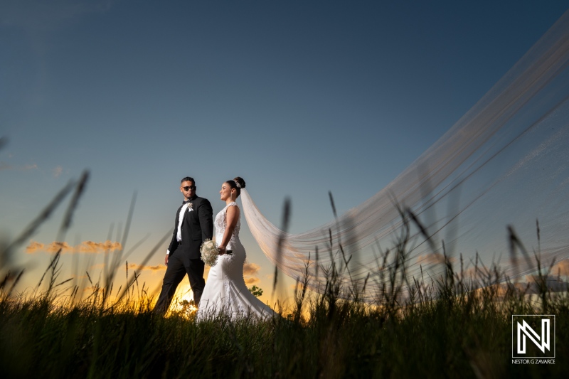 Couple walks together during sunset on their wedding day in Curacao with a beautiful sky and grass in the background