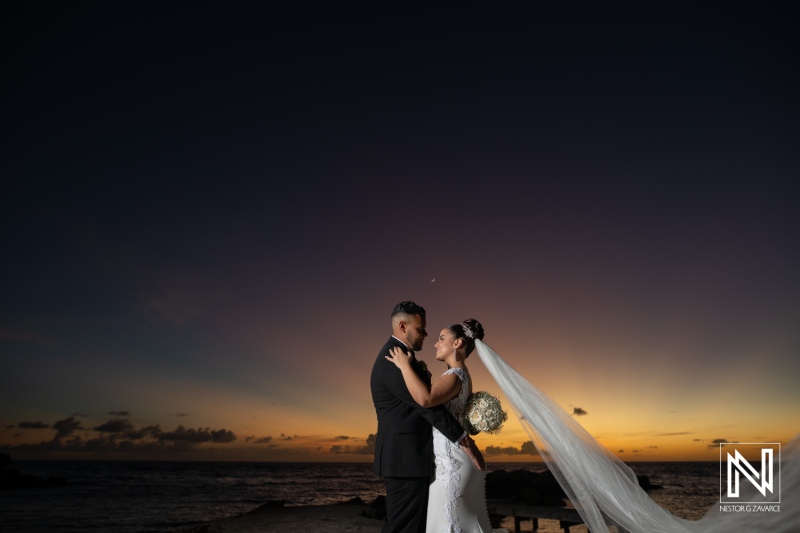 Couple celebrates wedding during sunset in Curacao with ocean background and beautiful sky colors