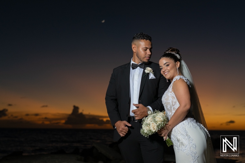 Couple celebrates wedding in Curacao with sunset as backdrop by the beach