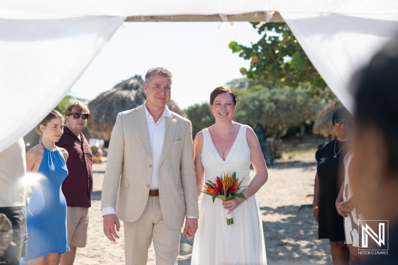 Couple celebrates their wedding at Daaibooi Beach in Curacao under a bright sky surrounded by guests and joyful atmosphere