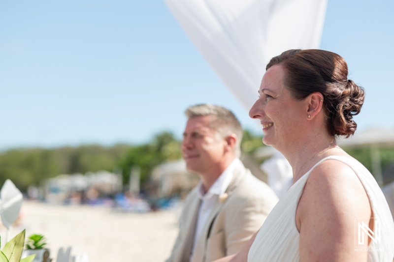 Beautiful wedding ceremony at Daaibooi Beach in Curacao under a clear blue sky with guests enjoying the joyful atmosphere