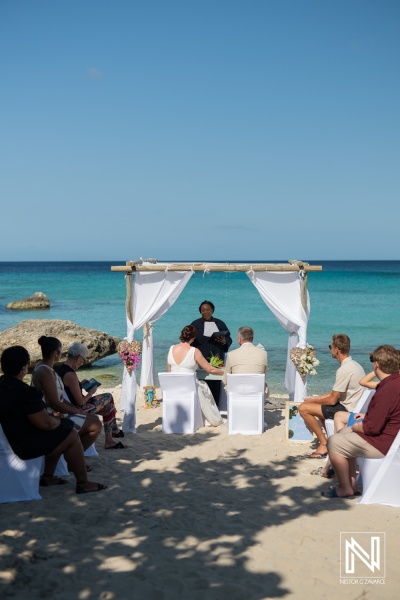 Wedding ceremony at Daaibooi Beach in Curacao embraces love and nature under a clear blue sky with family and friends in attendance