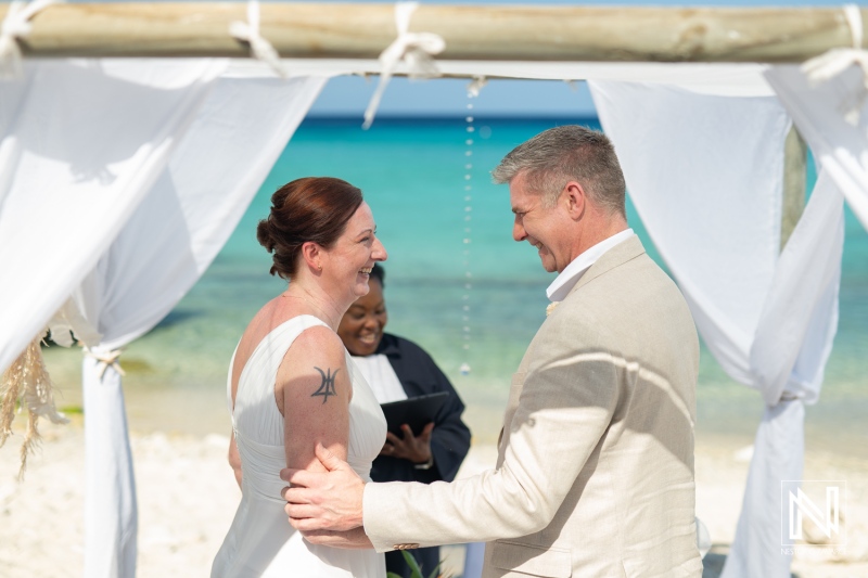 Couple exchanging vows during a beautiful wedding ceremony at Daaibooi Beach in Curacao under a scenic blue sky