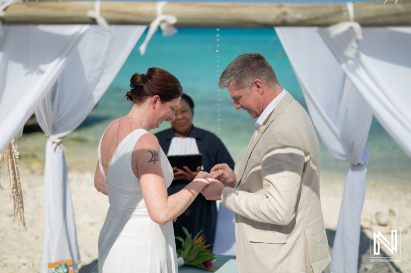 Couple exchanges vows at Daaibooi Beach wedding in Curacao under bright skies with calm turquoise waters