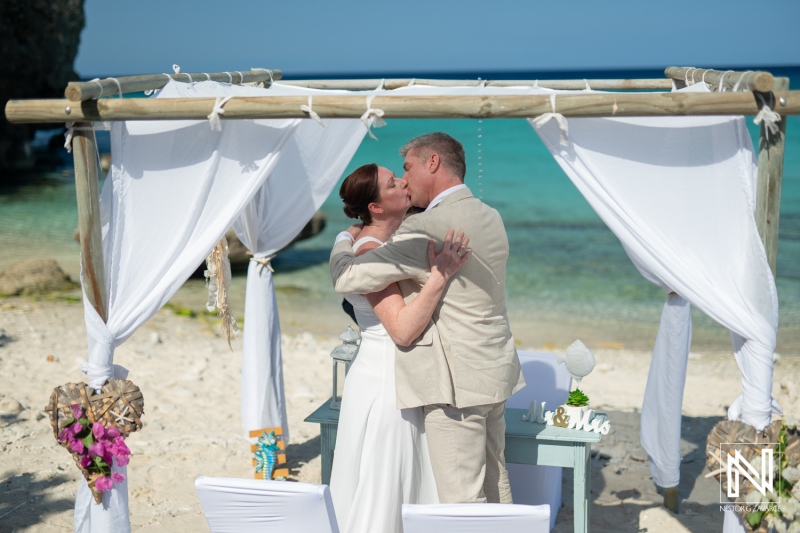 Couple embraces during a romantic wedding ceremony at Daaibooi Beach in Curacao on a sunny day with clear blue skies