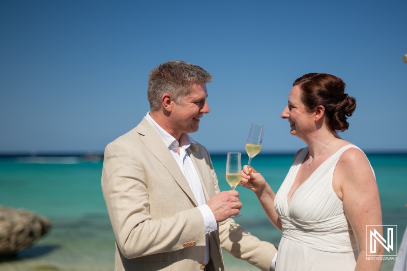 Couple celebrates love with champagne at Daaibooi Beach in Curacao during their wedding ceremony at sunset