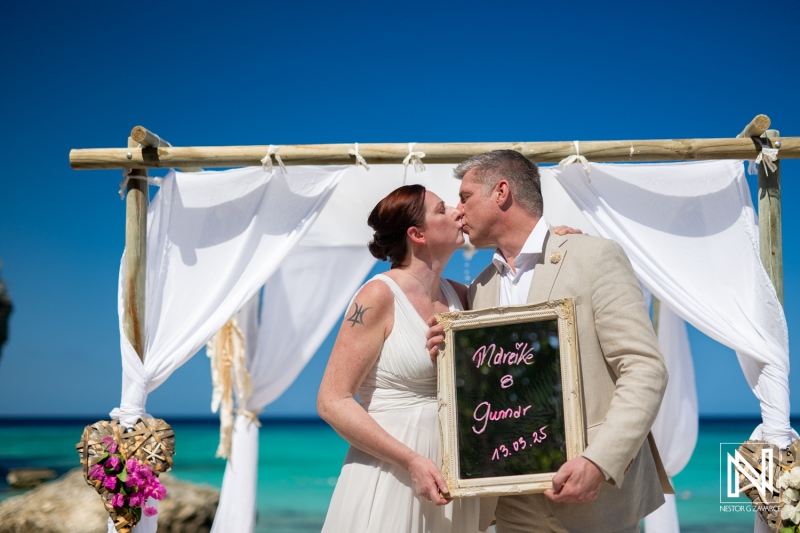 Couple celebrates their wedding at Daaibooi Beach in Curacao with a beautiful backdrop and an intimate kiss