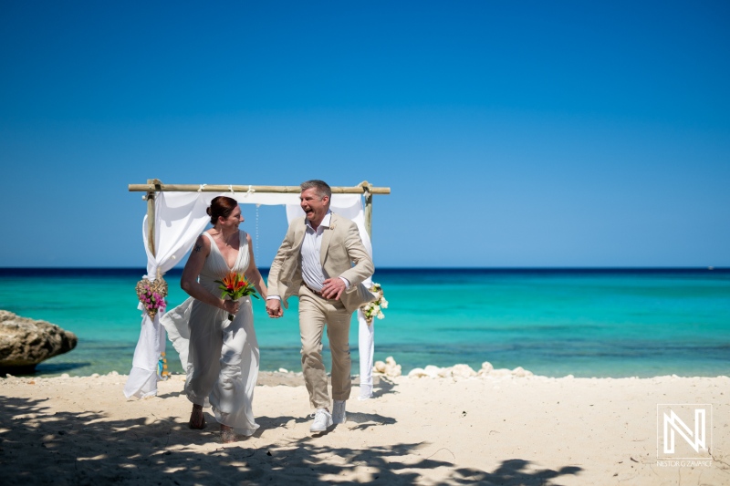 Couple celebrating a beautiful wedding ceremony at Daaibooi Beach in Curacao under clear blue skies and vibrant ocean waves