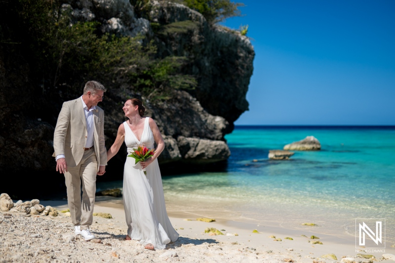 Wedding couple enjoying a romantic stroll at Daaibooi Beach in Curacao under the bright sun