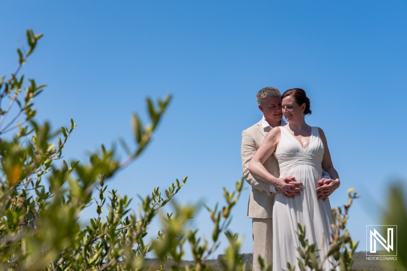 Couple celebrates their wedding in Willibrordus, Curacao, with a picturesque backdrop of lush green foliage and a clear blue sky