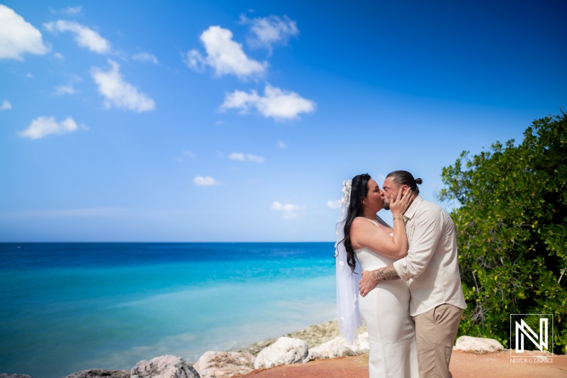 Couple shares a kiss during their wedding ceremony at Karakter in Curacao under clear blue skies