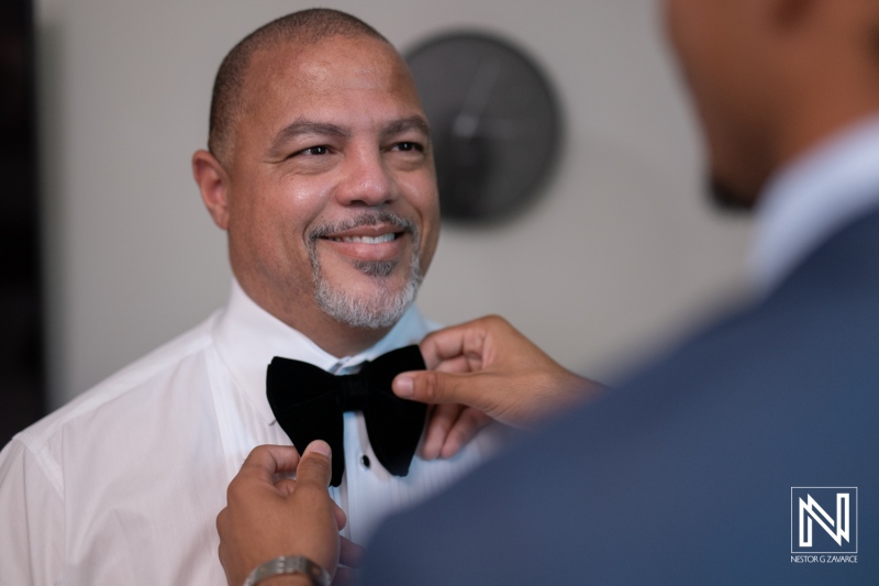 Groom prepares for wedding ceremony at Avila Beach Hotel in Curacao with assistance from a friend