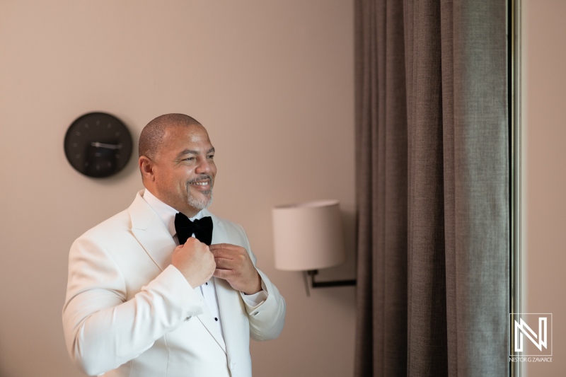 Groom preparing for wedding at Avila Beach Hotel in Curacao with elegant attire and joyful demeanor