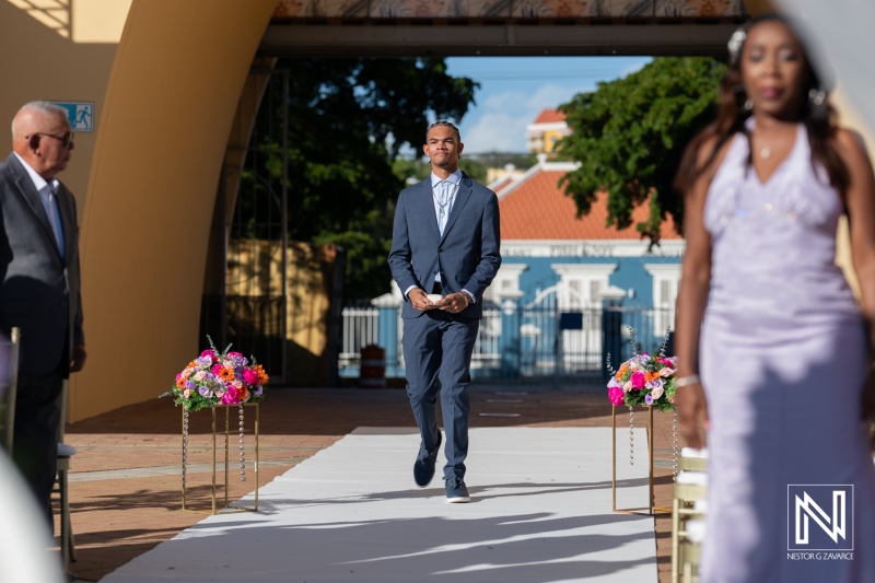 Groom walks toward altar in Curacao at Avila Beach Hotel during vibrant wedding ceremony filled with love