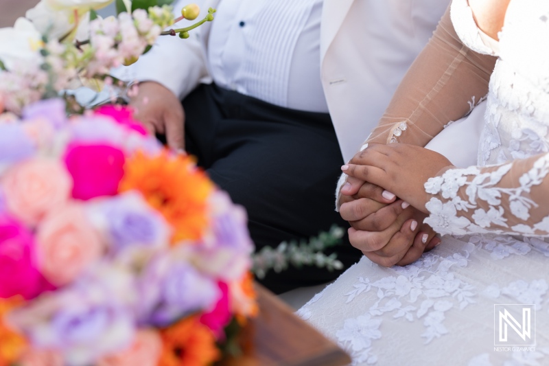 Couple exchanging vows at an outdoor wedding ceremony at Avila Beach Hotel in Curacao with vibrant floral arrangements and a heartfelt moment shared