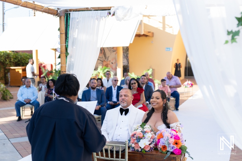 Wedding ceremony at Avila Beach Hotel in Curacao with a beautiful bride and groom surrounded by guests and floral arrangements