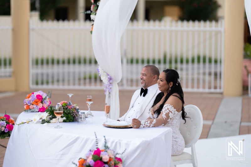Couple enjoying their wedding reception at Avila Beach Hotel in Curacao during sunset with floral decorations and elegant table setting