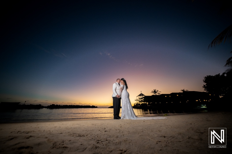 Couple shares a romantic moment at sunset during their wedding at Avila Beach Hotel in Curacao, creating lasting memories on the sandy beach