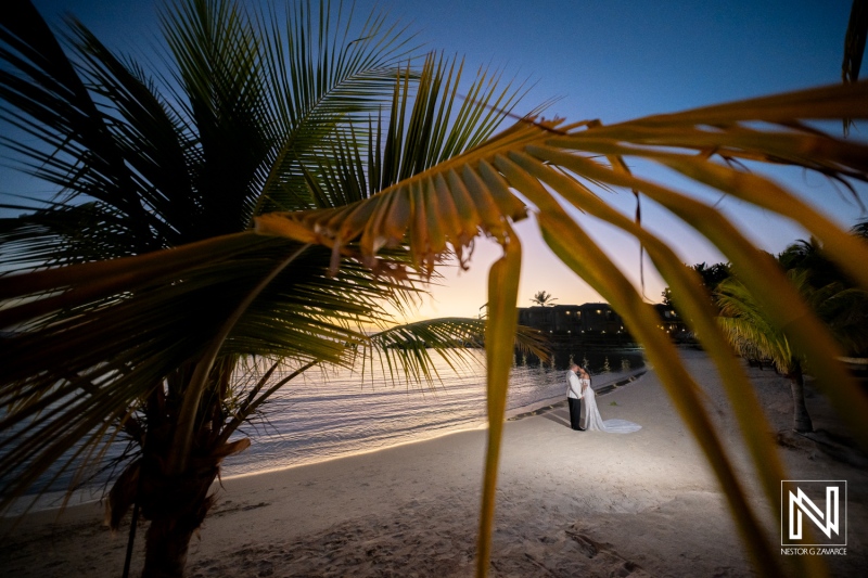 Beautiful wedding ceremony at Avila Beach Hotel in Curacao during sunset, with a couple standing on the beach surrounded by palm trees