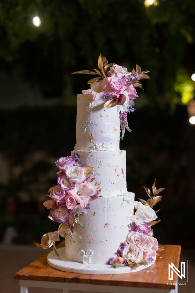 Elegant wedding cake adorned with fresh flowers at a beautiful beachfront ceremony in Curacao