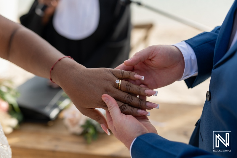Couple exchanging wedding rings at Renaissance Wind Creek Curacao Resort during a beachfront ceremony at sunset