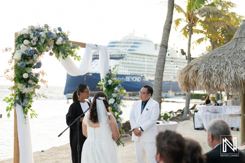 Elegant wedding ceremony on the beach at Renaissance Wind Creek Curacao Resort near a cruise ship