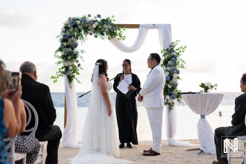 Wedding ceremony on the beach at Renaissance Wind Creek Curacao Resort with beautiful floral archway