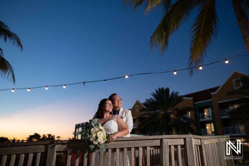 Beautiful wedding couple enjoying the sunset at Renaissance Wind Creek Curacao Resort with palms and string lights