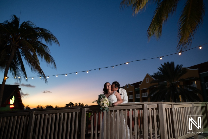 Romantic wedding couple embraces on a deck at sunset in Curacao, creating unforgettable memories at Renaissance Wind Creek Curacao Resort