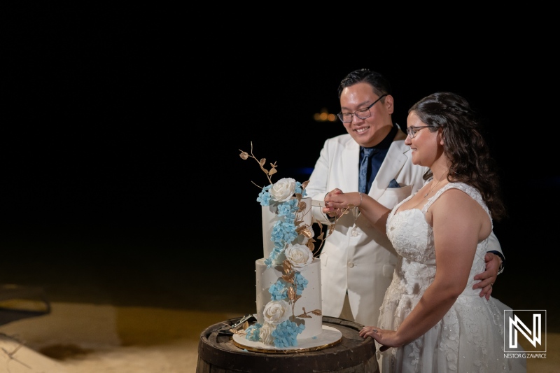 Couple celebrating wedding at Renaissance Wind Creek Curacao Resort with a stunning cake under the stars