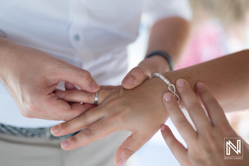 Couple exchanges wedding rings during a romantic ceremony at Daaibooi beach in Curacao under a bright sunny sky