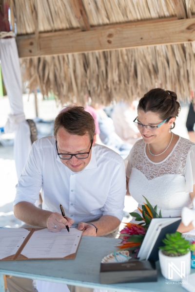 Couple signs marriage certificate on the beach in Daaibooi, Curacao during a charming wedding ceremony