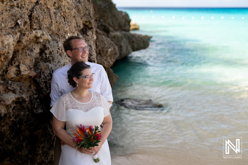 Couple celebrating their wedding by the beautiful Daaibooi beach in Curacao with vibrant flowers and picturesque ocean backdrop