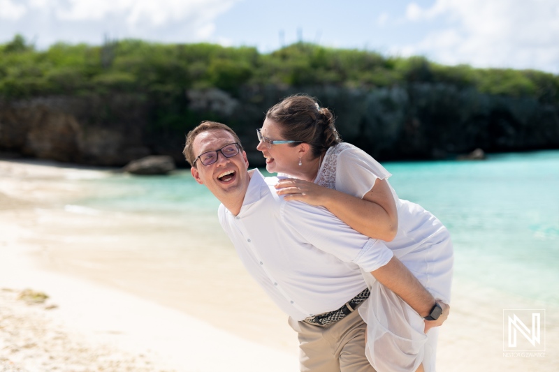 Couple celebrating their wedding at Daaibooi Beach in Curacao under a bright sky with turquoise waters in the background