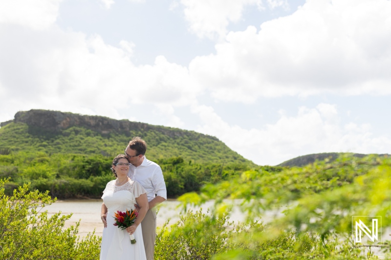 Couple celebrates their wedding at Daaibooi beach in Curacao under a bright sky and lush green landscape