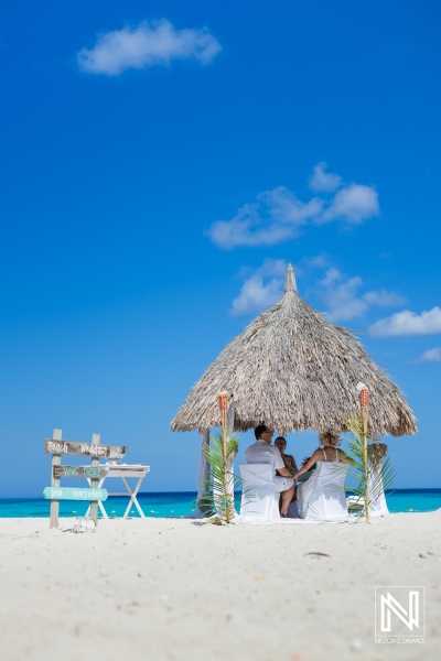 A Couple Exchanging Vows Under a Thatched Hut on a Beautiful Beach With Clear Blue Skies and Gentle Waves in the Background, Capturing a Serene Moment of Love and Commitment