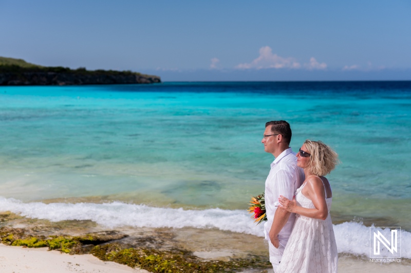 A Couple Enjoying a Romantic Stroll on a Beautiful Tropical Beach With Vibrant Blue Waters, Surrounded by Lush Greenery Under a Clear Sky