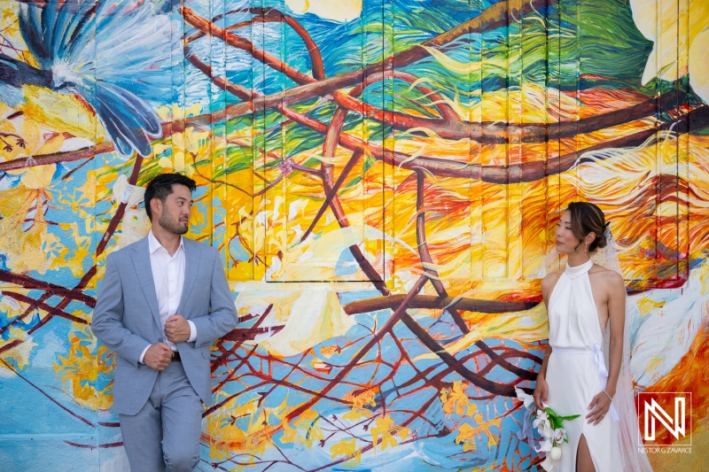 Couple stands in front of colorful mural during wedding ceremony in Playa Hunku, Curacao